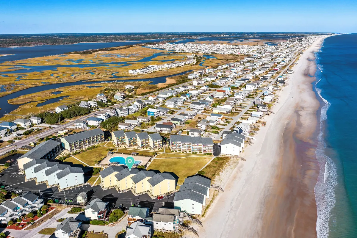 This vibrant exterior image captures a sweeping view of the ocean, sandy beachfront, sparkling swimming pool, and the residential buildings of Surf Condos. The open, inviting atmosphere is perfect for morning beach walks, sunset strolls, and offers a direct connection to the pet-friendly activities mentioned in the section.