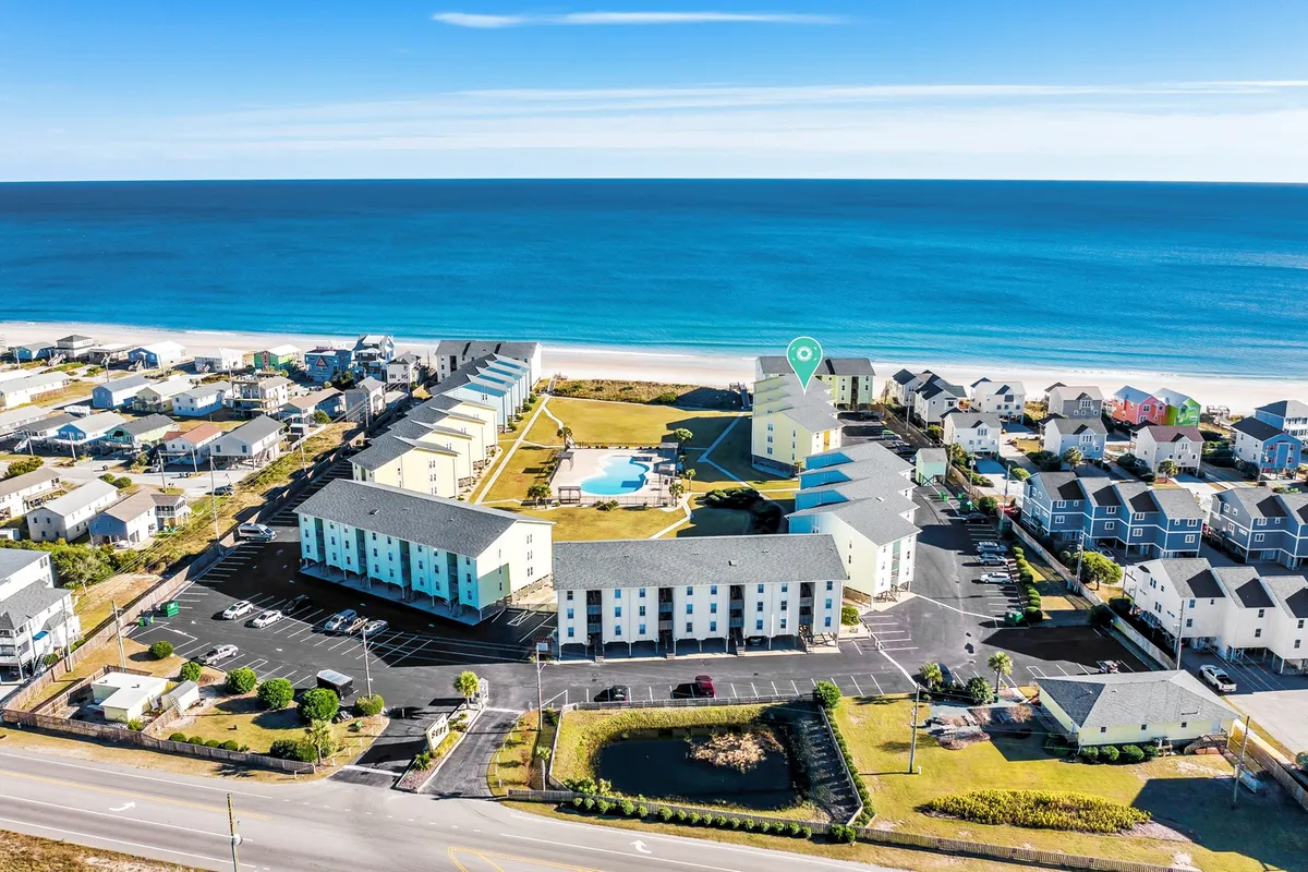 A cheerful exterior shot featuring a beachfront view with a swimming pool and vivid, colorful buildings. The beach is easily accessible, and the surroundings evoke a sense of relaxed outdoor living—a perfect backdrop for exploring with pets or relaxing at a seaside café patio.
