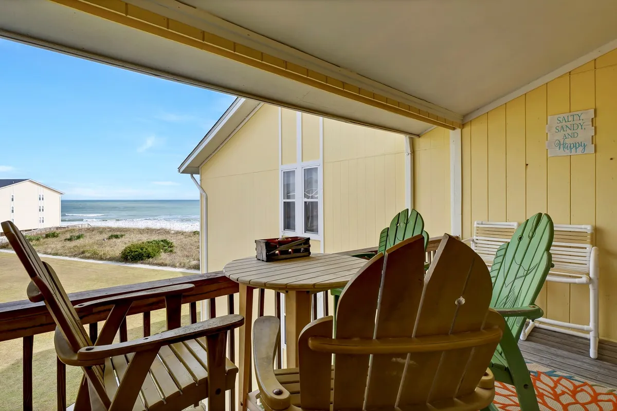 A cheerful balcony scene with colorful chairs, a table, and a clear view of the ocean. The inviting setup is perfect for relaxing, socializing, or enjoying a meal or drinks while gazing at the sunrise or sunset over the Atlantic.