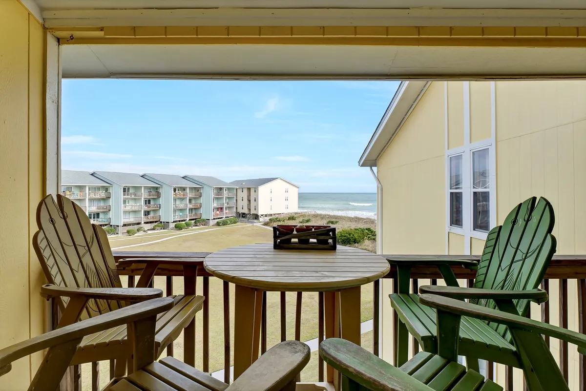 This image shows a serene balcony setting featuring Adirondack chairs and a table, all overlooking an unobstructed view of the ocean. The tranquil blue water stretches out to the horizon, and the balcony provides an intimate spot for relaxing, sipping coffee, or sharing moments with loved ones while watching the sunrise or sunset.